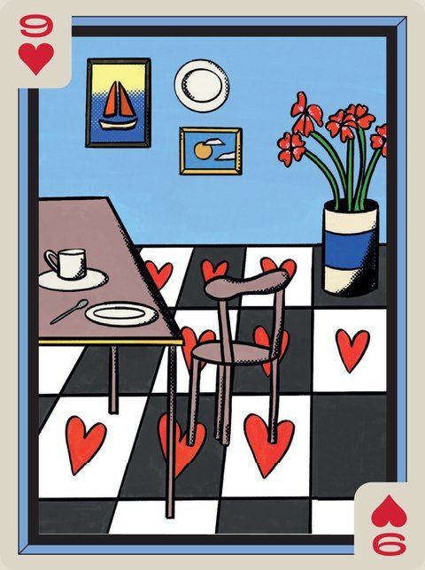 A kitchen corner with a black and white floor of hearts, a table and red flowers.