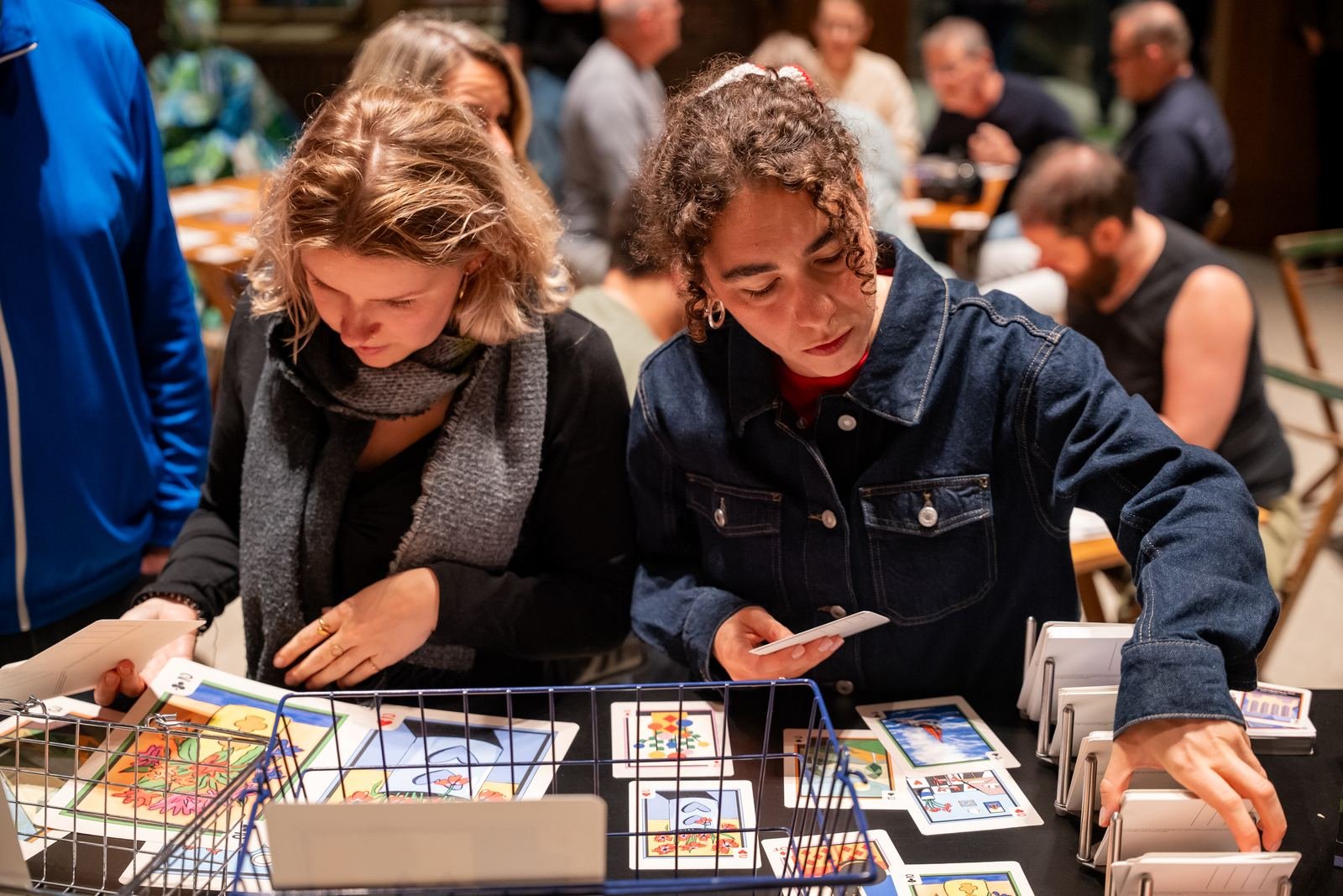 Two visitors browse Gallery Gambit cards in wire baskets at the stand.
