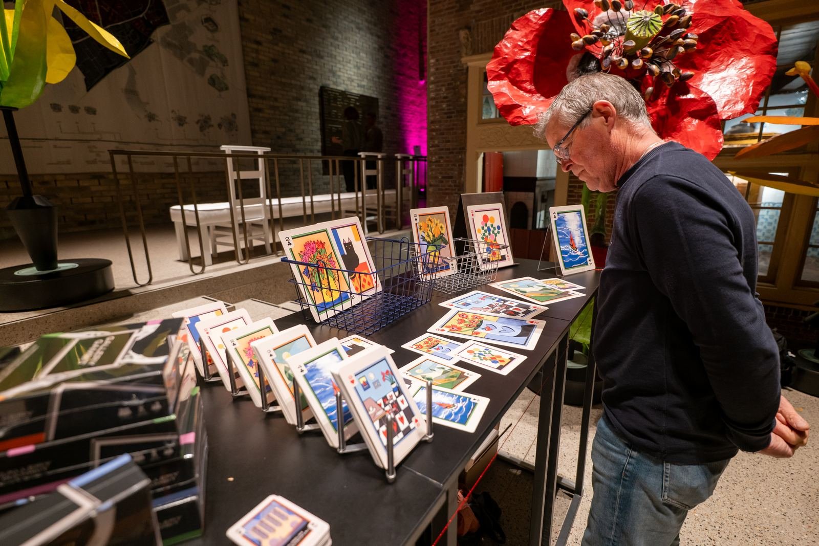 A visitor studies Gallery Gambit cards displayed upright on a long table.
